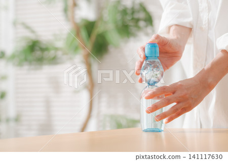 一位女士正在打開一瓶彈珠汽水(日本汽水)。 一位女士正在打開一瓶彈珠汽水(日本汽水)。 141117630