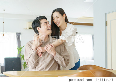 一位年輕的日本女子在客廳裡摟著一位男子的手臂。 一位年輕的日本女子在客廳裡摟著一位男子的手臂。 141117921
