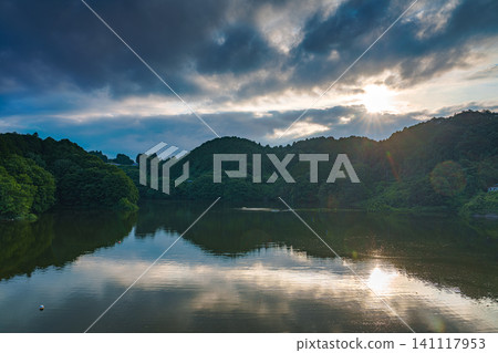 Scenery of the Yamatoji region: Nunome Dam in Nara City - Beautiful sunset sky and reflection on the lake surface - Sunset illuminating the lake surface through the clouds ① Scenery of the Yamatoji region: Nunome Dam in Nara City - Beautiful sunset sky and reflection on the lake surface - Sunset illuminating the lake surface through the clouds ① 141117953
