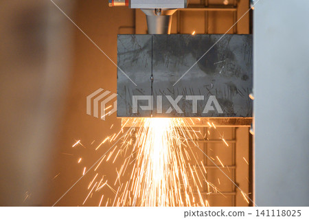 Side view of a high-precision fiber laser cut machine operation cutting a steel tube with sparkling light. 141118025