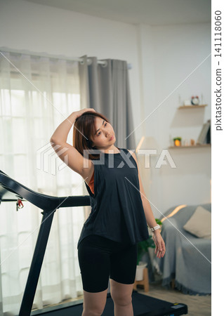 Young woman stretching neck muscles after exercising on treadmill at home Young woman stretching neck muscles after exercising on treadmill at home 141118060