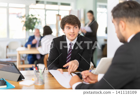Consultant of a modern bank office tells a man about deposits and savings accounts 141118109