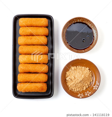crispy fried glutinous rice cakes served on a black plate with brown sugar syrup and soybean powder dips crispy fried glutinous rice cakes served on a black plate with brown sugar syrup and soybean powder dips 141118119