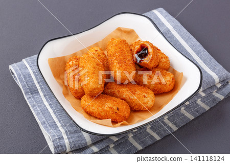 stack of crispy fried glutinous rice cakes with oozing black brown sugar filling in a bowl, dark wooden background 141118124