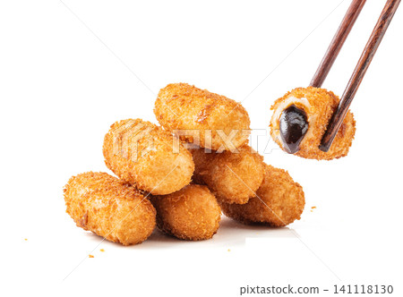 chopsticks lifting a piece of crispy fried glutinous rice cake showing molten brown sugar syrup filling, white background chopsticks lifting a piece of crispy fried glutinous rice cake showing molten brown sugar syrup filling, white background 141118130