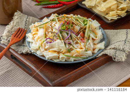 shaanxi style flavored Liangpi cold noodles with peanut sauce, cucumber, and onion on a wooden tray shaanxi style flavored Liangpi cold noodles with peanut sauce, cucumber, and onion on a wooden tray 141118184