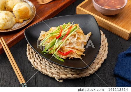 shaanxi style Liangpi cold starch noodles with cucumber shreds and chili oil on a blue plate 141118214
