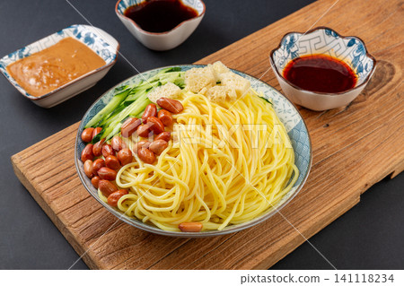 northeast Chinese style cold yellow noodles with peanuts, cucumber, and dipping sauces on a wooden board northeast Chinese style cold yellow noodles with peanuts, cucumber, and dipping sauces on a wooden board 141118234