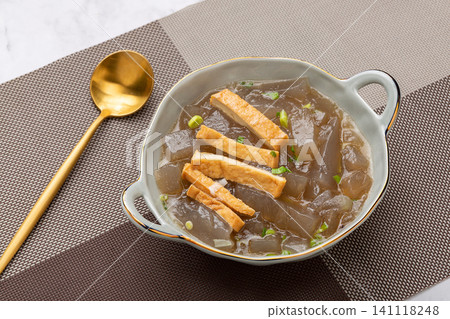 traditional Chinese sweet potato starch jelly soup with tofu cubes and green onions in a ceramic bowl 141118248