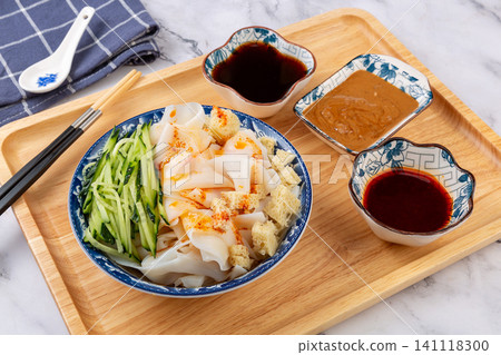 shaanxi style Liangpi cold starch noodles with cucumber shreds, gluten cubes, and traditional dipping sauces, top view shaanxi style Liangpi cold starch noodles with cucumber shreds, gluten cubes, and traditional dipping sauces, top view 141118300