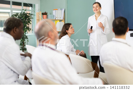 Adult female doctor presenting with remote control in meeting room Adult female doctor presenting with remote control in meeting room 141118332