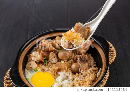 Chinese claypot rice with pork ribs, straw mushrooms and sunny side up egg on white wooden table Chinese claypot rice with pork ribs, straw mushrooms and sunny side up egg on white wooden table 141118484