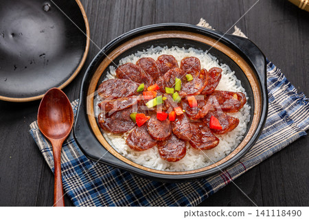 Cantonese claypot rice with sliced Chinese sausage, spoon lifting crispy scorched rice crust 141118490