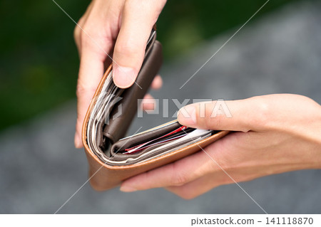 A man's hand holding a wallet with its contents in a mess. A man's hand holding a wallet with its contents in a mess. 141118870