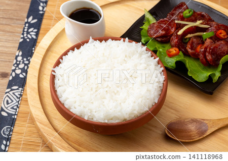 A bowl of freshly cooked fluffy white rice in a traditional ceramic bowl with chopsticks on a rustic wooden table. A bowl of freshly cooked fluffy white rice in a traditional ceramic bowl with chopsticks on a rustic wooden table. 141118968