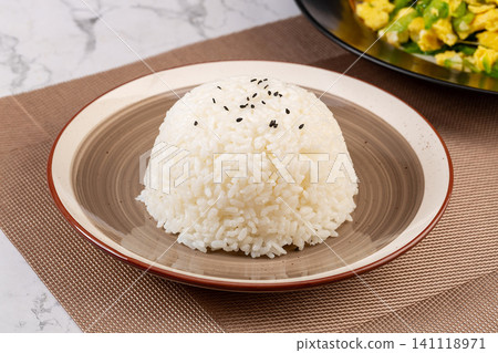 A neat dome shaped serving of steamed white rice sprinkled with black sesame seeds on a plate, asian staple food background 141118971