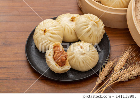 Traditional Chinese breakfast steamed meat buns served on a ceramic plate with rustic wooden decor. Traditional Chinese breakfast steamed meat buns served on a ceramic plate with rustic wooden decor. 141118993