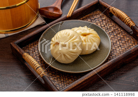 Traditional Chinese breakfast steamed meat buns served on a ceramic plate with rustic wooden decor. Traditional Chinese breakfast steamed meat buns served on a ceramic plate with rustic wooden decor. 141118998