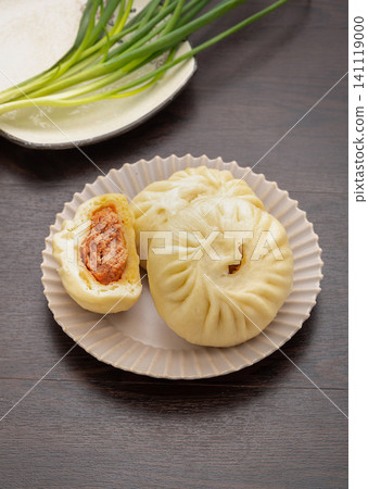 Traditional Chinese breakfast steamed meat buns served on a ceramic plate with rustic wooden decor. Traditional Chinese breakfast steamed meat buns served on a ceramic plate with rustic wooden decor. 141119000