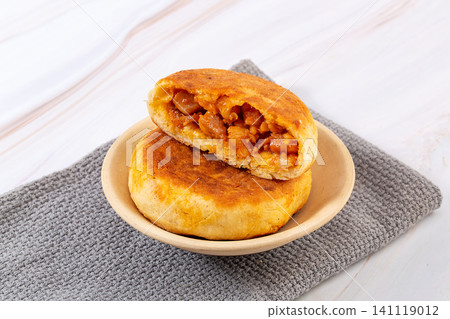 chinese pan fried meat pies stuffed with New Orleans chicken chunks in white ceramic bowl 141119012