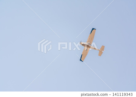 Small ultralight airplane with overhead wing and single propeller flying in sunset sky. Small ultralight airplane with overhead wing and single propeller flying in sunset sky. 141119343