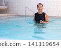 A smiling senior man doing water walking in a swimming pool. 141119654