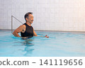 A smiling senior man doing water walking in a swimming pool. 141119656