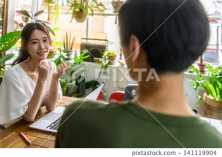 A young Japanese woman smiles and talks while operating a computer. A young Japanese woman smiles and talks while operating a computer. 141119904