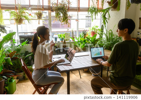 A man and a woman working on their PCs in a room surrounded by greenery. A man and a woman working on their PCs in a room surrounded by greenery. 141119906