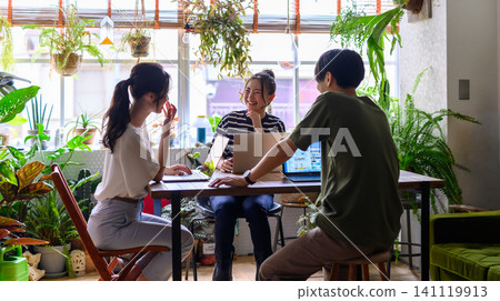 People working on their PCs in a room surrounded by greenery. 141119913