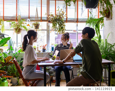 三個人在擺滿室內植物的辦公室裡使用筆記型電腦。 三個人在擺滿室內植物的辦公室裡使用筆記型電腦。 141119915