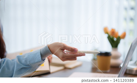 Hand holding pills during online learning session at bright home workspace with coffee and copy space 141120389