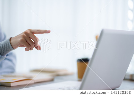 Hand pointing at laptop screen during online education lesson in bright modern workspace with copy space Hand pointing at laptop screen during online education lesson in bright modern workspace with copy space 141120398
