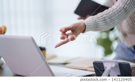 Woman pointing at laptop screen during online education tutorial session in bright home office with copy space Woman pointing at laptop screen during online education tutorial session in bright home office with copy space 141120405