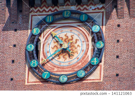 Antique Astronomical Clock on the Brick Castle Tower with a Golden Sun Dial and Numbers. Milan Castle wall tower facade. Italian architecture Antique Astronomical Clock on the Brick Castle Tower with a Golden Sun Dial and Numbers. Milan Castle wall tower facade. Italian architecture 141121063
