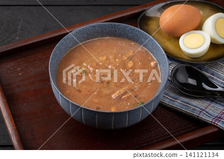 traditional Chinese savory millet porridge Doumo in a blue ceramic bowl, served with boiled eggs for breakfast. 141121134
