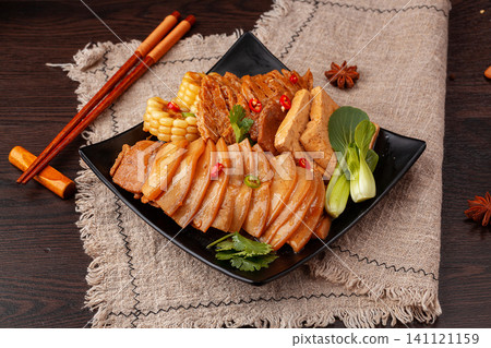 slices of braised pork belly served with sweet corn and tofu in traditional Chinese style on a black plate. slices of braised pork belly served with sweet corn and tofu in traditional Chinese style on a black plate. 141121159