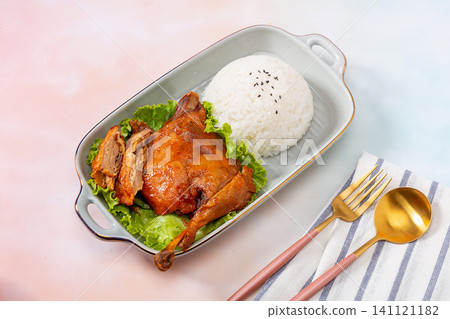 roasted duck leg with crispy skin served with steamed rice and lettuce in a ceramic dish. roasted duck leg with crispy skin served with steamed rice and lettuce in a ceramic dish. 141121182