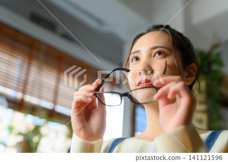 A woman takes off her glasses and looks into the distance. A woman takes off her glasses and looks into the distance. 141121596