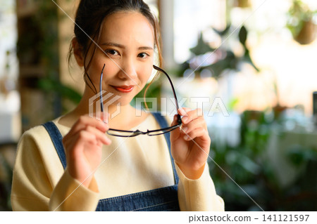 A young Japanese woman smiles after taking off her glasses. A young Japanese woman smiles after taking off her glasses. 141121597