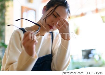 A woman closes her eyes, feeling tired. A woman closes her eyes, feeling tired. 141121598