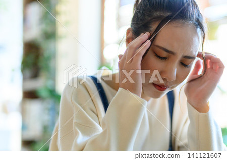 A woman holding her head in her hands in distress. A woman holding her head in her hands in distress. 141121607