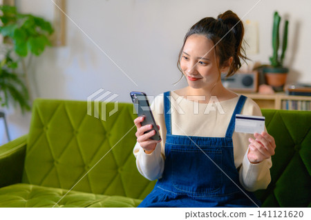 A woman looking at her smartphone and cards on the sofa. A woman looking at her smartphone and cards on the sofa. 141121620