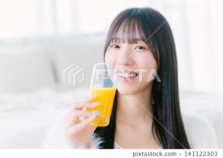 一位年輕女子在房間裡喝著柳橙汁 141122303