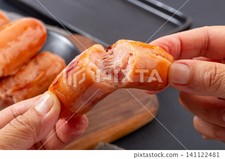 hands Pulling Apart Juicy Grilled Taiwanese Pork Sausage Showing Meat Texture hands Pulling Apart Juicy Grilled Taiwanese Pork Sausage Showing Meat Texture 141122481