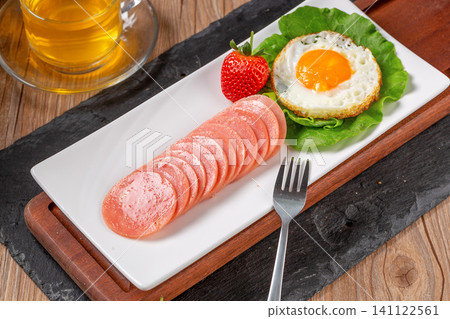 breakfast set with sliced round ham, fried egg, strawberry and tea breakfast set with sliced round ham, fried egg, strawberry and tea 141122561
