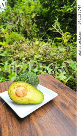 Avocado on a white plate and avocado cut in half 141122744