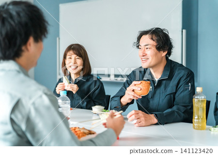Businessmen and women in work clothes eating lunch in the break room Businessmen and women in work clothes eating lunch in the break room 141123420