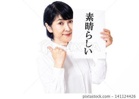 A middle-aged woman in a white shirt smiles at the camera, holding a sign that says "Wonderful." 141124426