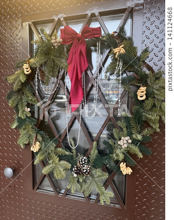 Elegant christmas wreath with red bow and crystal beads on a brown door, festive holiday entrance decoration concept. Elegant christmas wreath with red bow and crystal beads on a brown door, festive holiday entrance decoration concept. 141124668
